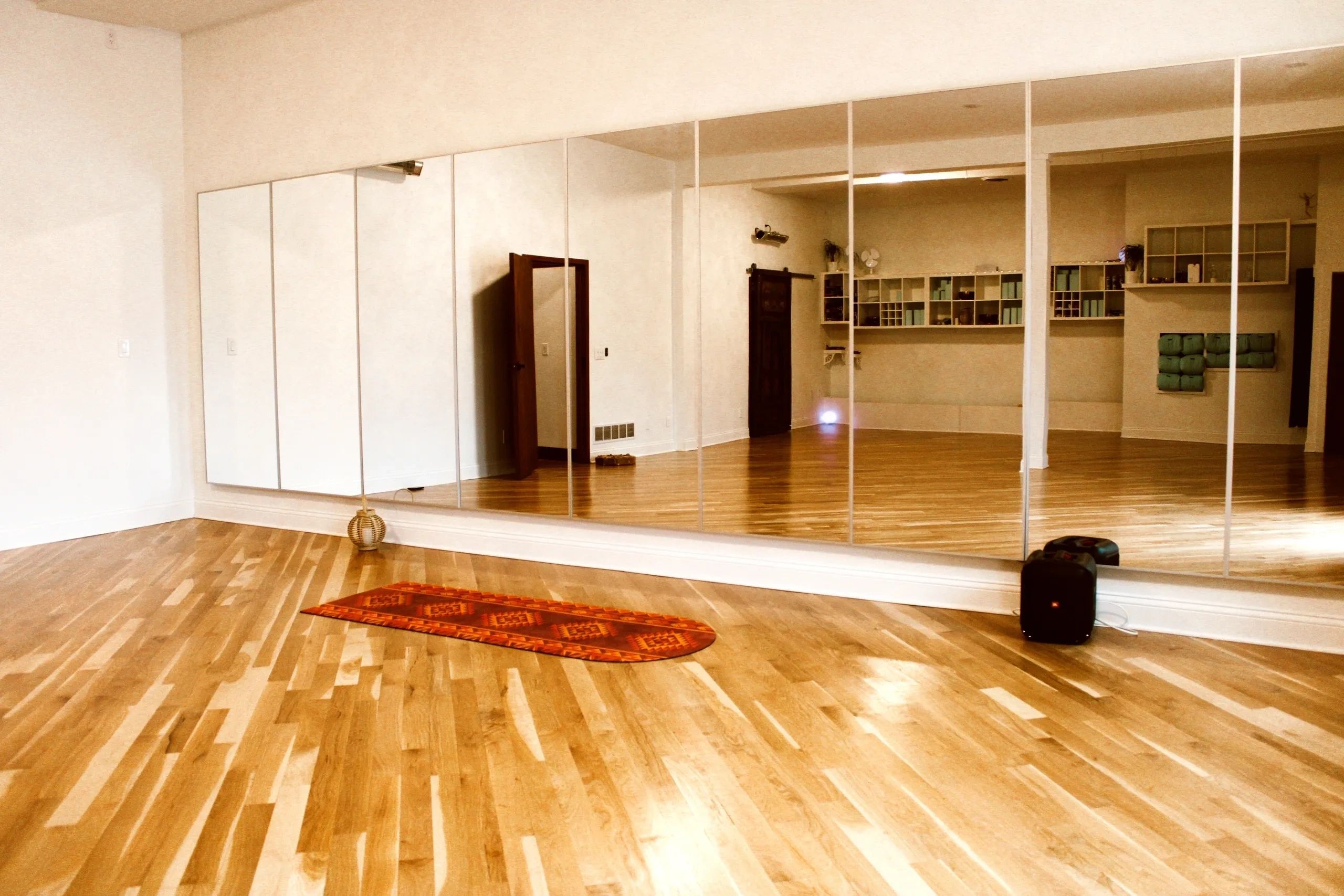 The Yoga Pad studio with wood floors, mirrors, and yoga props